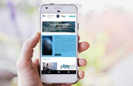 Photo d'une main tenant un smartphone sur lequel est affichée la newsletter OneWater