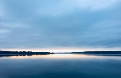Photo du soleil se couchant à l'horizon sur un lac 