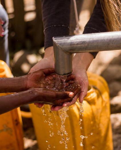 Photo de deux paires de main recueillant de l'eau sous un robinet