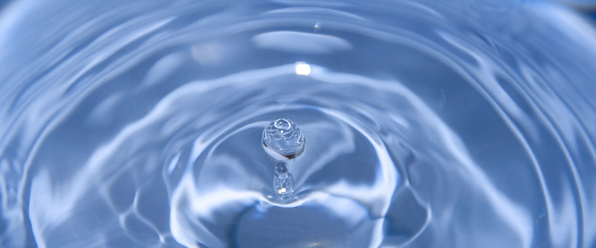 Photo d'une goutte tombant sur une surface aqueuse et créant des ondes