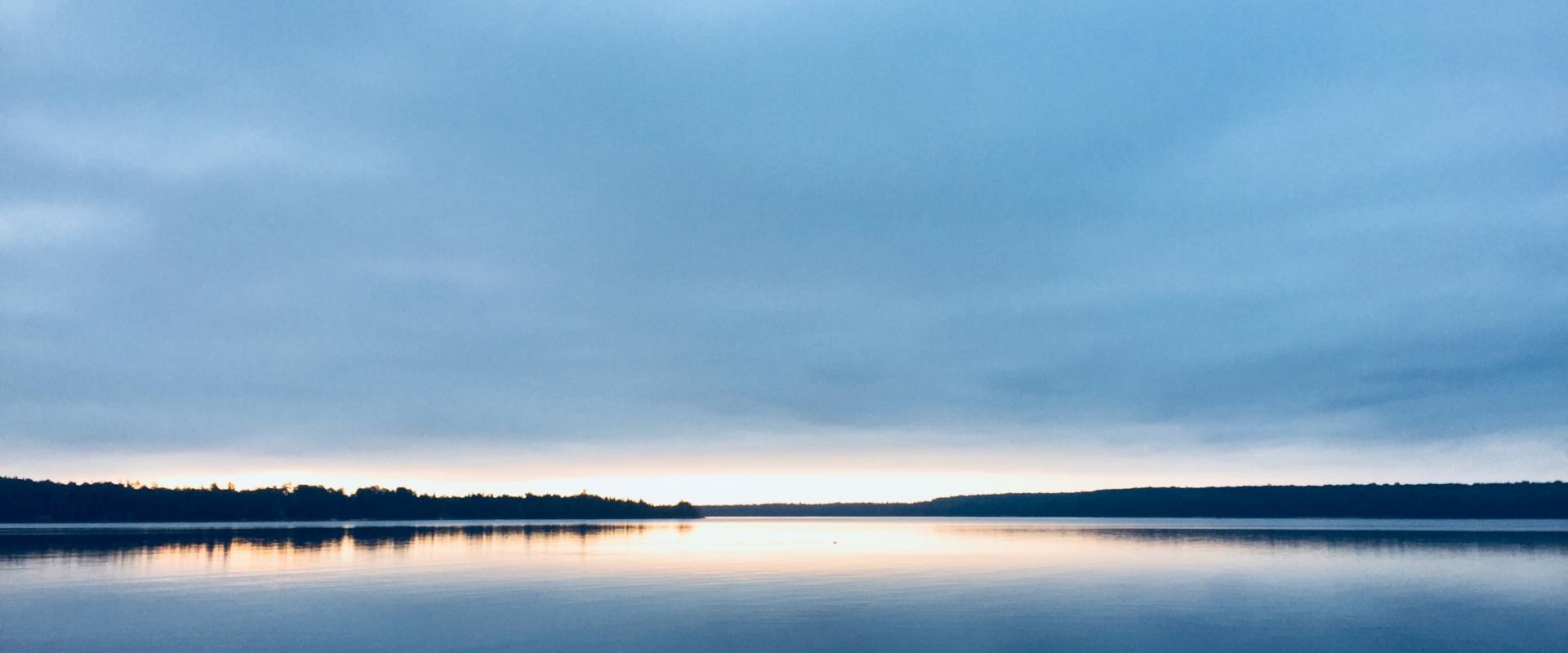 Photo du soleil se couchant à l'horizon sur un lac 