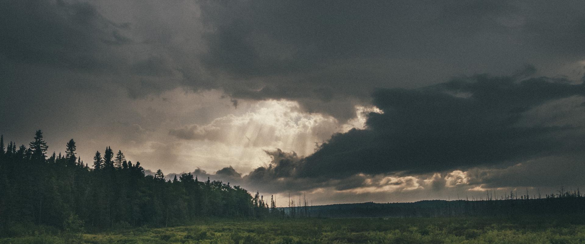 Photo d'une mare dans une prairie sous un ciel orageux