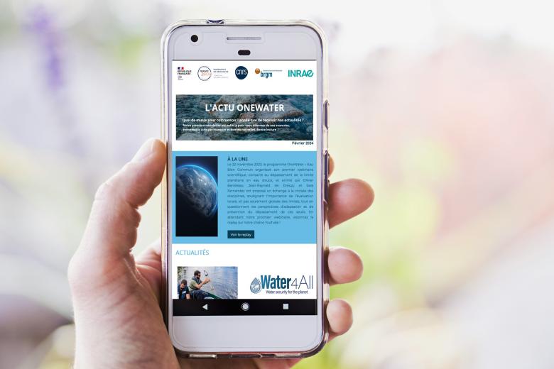 Photo d'une main tenant un smartphone sur lequel est affichée la newsletter OneWater